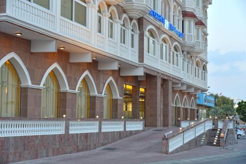 a large building on a street next to a sidewalk at Muscat Plaza Hotel in Muscat