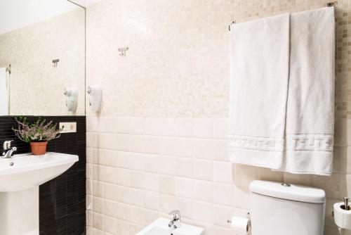 a bathroom with a white toilet and a sink at Suites Campo del Príncipe by Maxi Hoteles in Granada