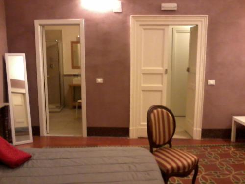 a bedroom with a bed and a chair and a mirror at Domoikos in Catania