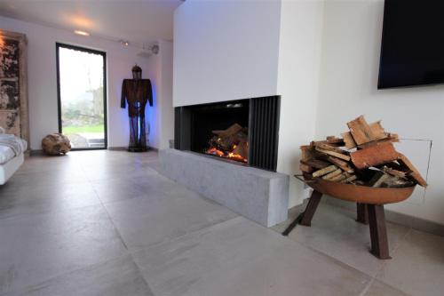 a living room with a fireplace and a pile of wood at ARVAK HEYD (DURBUY) in Heyd