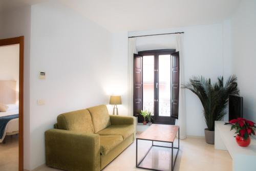 a living room with a chair and a table at Suites Campo del Príncipe by Maxi Hoteles in Granada