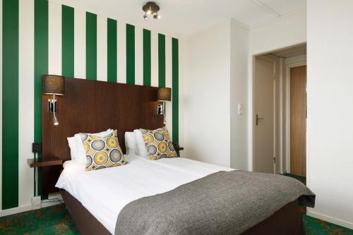 a bedroom with a bed with green and white stripes at ProfilHotels Hotel Garden in Malmö