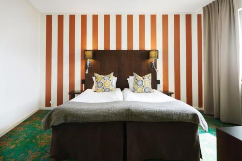 a bedroom with a large bed with orange and white stripes at ProfilHotels Hotel Garden in Malmö