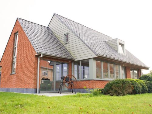 a red brick house with a gray roof at Beautiful villa with private garden in Alveringem