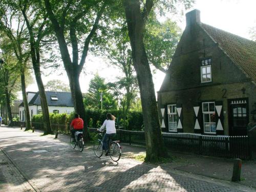 two people riding bikes in front of a house at 't STRANDHUYS en DE VUURTOREN, met eigen KEUKEN, ZONNIG TERRAS nabij DORP, DUINEN en STRAND, Incl verwarmd binnen ZWEMBAD in Hollum