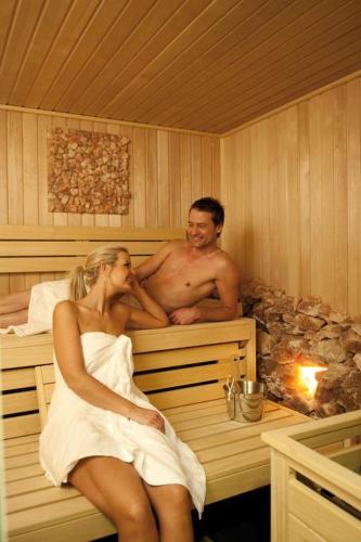 a man and a woman sitting in a sauna at 't STRANDHUYS en DE VUURTOREN, met eigen KEUKEN, ZONNIG TERRAS nabij DORP, DUINEN en STRAND, Incl verwarmd binnen ZWEMBAD in Hollum