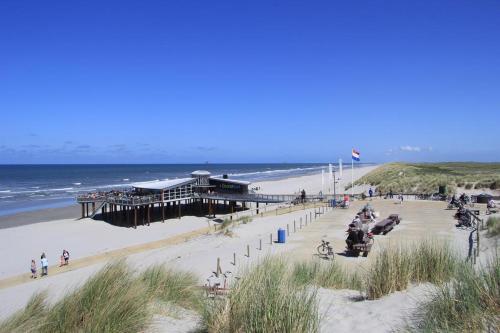 a pier on a beach next to the ocean at 't STRANDHUYS en DE VUURTOREN, met eigen KEUKEN, ZONNIG TERRAS nabij DORP, DUINEN en STRAND, Incl verwarmd binnen ZWEMBAD in Hollum