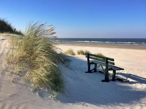 a bench sitting on a beach near the ocean at 't STRANDHUYS en DE VUURTOREN, met eigen KEUKEN, ZONNIG TERRAS nabij DORP, DUINEN en STRAND, Incl verwarmd binnen ZWEMBAD in Hollum