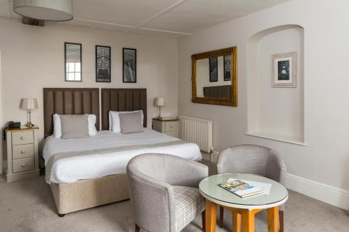 a bedroom with a bed and two chairs and a table at Royal Hotel in Deal