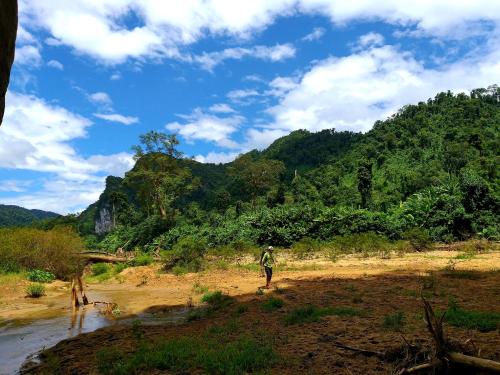 a man walking on a dirt road next to a mountain at Charm's Homestay in Phong Nha