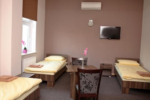 a room with two beds and a table and a tv at Noclegi Gemini Dom in Elblag