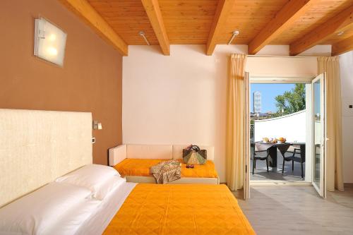 a bedroom with a bed and a balcony with a table at Hotel Favorita in Cesenatico
