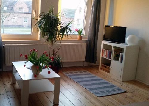 uma sala de estar com televisão e uma mesa com flores em Hof Heideland 1 em Eichholz