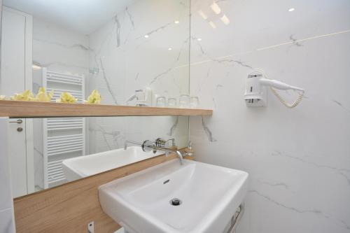 a white bathroom with a sink and a mirror at Hotel San Antonio in Podstrana