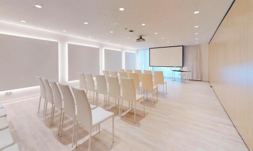 a conference room with white chairs and a screen at Meliá Calviá Beach in Magaluf