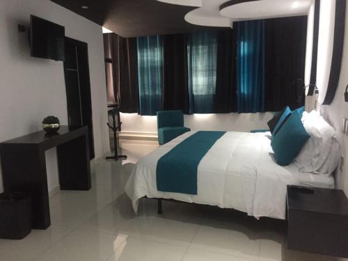a bedroom with a bed with a blue and white blanket at Hotel Dluxe in San Juan de los Lagos
