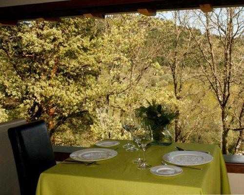 a green table with plates and wine glasses on it at Hotel Rural Las Rozuelas in Cercedilla