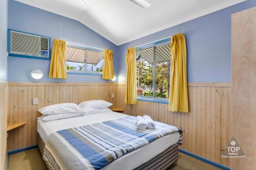 a bedroom with a bed and two windows at Lake Tinaroo Holiday Park in Tinaroo