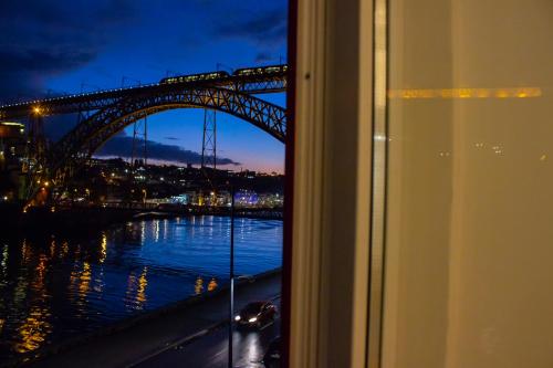 a view of a bridge at night from a window at Red House By The River in Porto