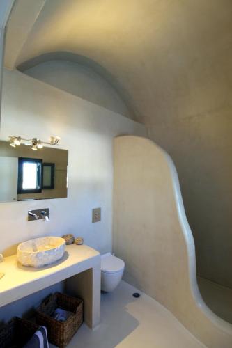 a bathroom with a toilet and a sink and a mirror at Filira Suites in Perissa