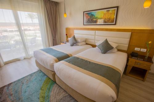 a hotel room with two beds and a window at Pickalbatros Aqua Blu Sharm El Sheikh in Sharm El Sheikh