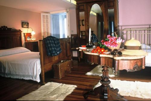 ein Schlafzimmer mit einem Bett und einem Tisch mit Blumen darauf in der Unterkunft Casa das Calhetas - Turismo de Habitação in Calhetas