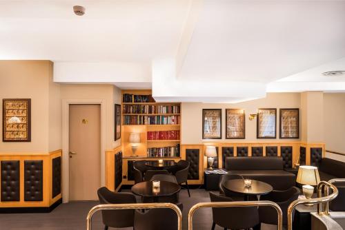 un soggiorno con divani, tavoli e librerie di Hotel Mentana, by R Collection Hotels a Milano