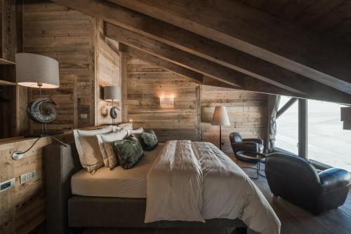 a bedroom with a bed in a room with wooden walls at Sunny Valley Mountain Lodge in Bormio