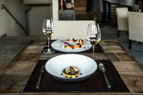 a table with two plates of food and two glasses of wine at Sunny Valley Mountain Lodge in Bormio