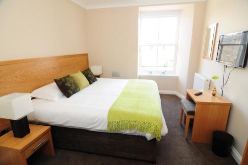 a bedroom with a bed and a desk and a window at Station House - Room Only in Aberfeldy