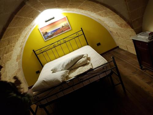 Cama en habitación con pared amarilla en La tana del pescatore, en Brindisi