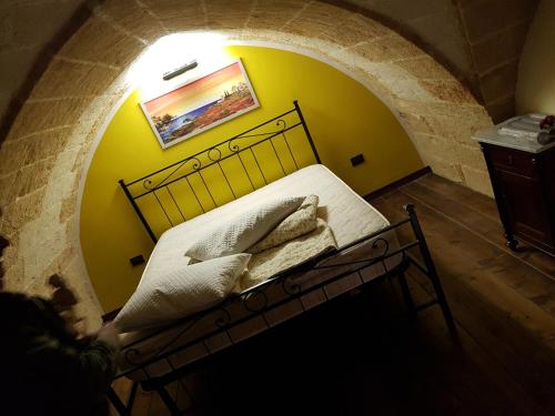 a bed in a room with a yellow wall at La tana del pescatore in Brindisi