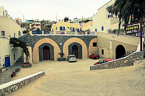 a building with arches and cars parked on a street at Anatoli Hotel & Spa in Fira
