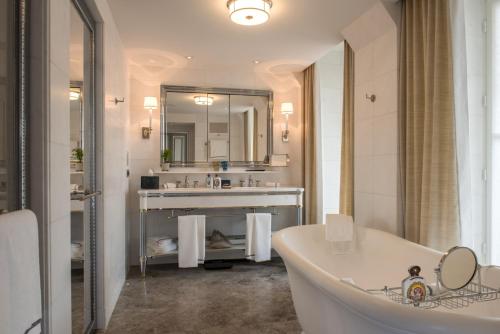
a bathroom with a tub, sink and mirror at Hotel de Crillon in Paris
