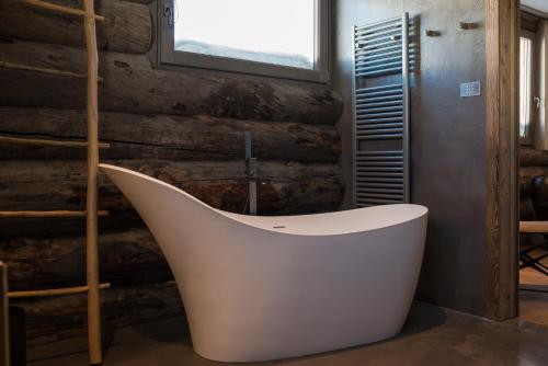 a bath tub in a room with a wooden wall at Sunny Valley Mountain Lodge in Bormio