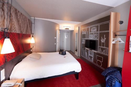 a hotel room with a large white bed and a red carpet at ibis Cholet in Cholet