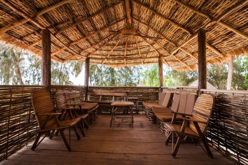 a porch with chairs and tables and a thatched roof at Gîte du Lac in Niaga