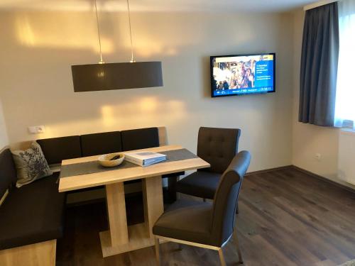 a dining room with a table and chairs and a tv at Harry´s Appartement in Pettneu am Arlberg