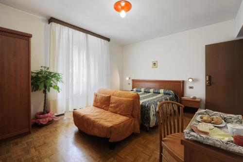 a bedroom with a bed and a chair and a table at Hotel Bertusi in Porretta Terme