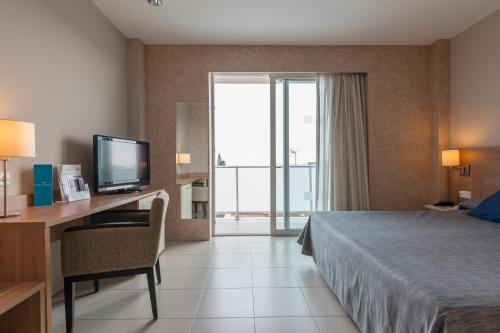 Habitación de hotel con cama y escritorio con TV. en Hotel Lodomar Spa & Talasoterapia en San Pedro del Pinatar