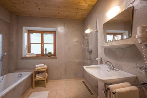 uma casa de banho com um lavatório, uma banheira e um espelho. em Ferienhaus Bockstecken em Hart im Zillertal