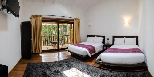 1 dormitorio con 2 camas, ventana y alfombra en Bamboo Lodge Sacred Valley, en Písac