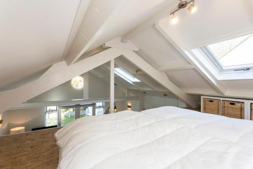 a bedroom with a large white bed with a skylight at Holiday home Beach bubbles - near the beach with big garden - not for companies in Ouddorp