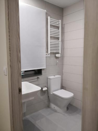 a white bathroom with a toilet and a sink at A Torre do Lago in Valdoviño