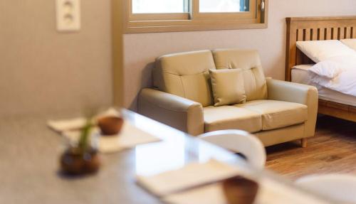a room with a couch and a chair and a bed at Gyeongpoen Pension in Gangneung