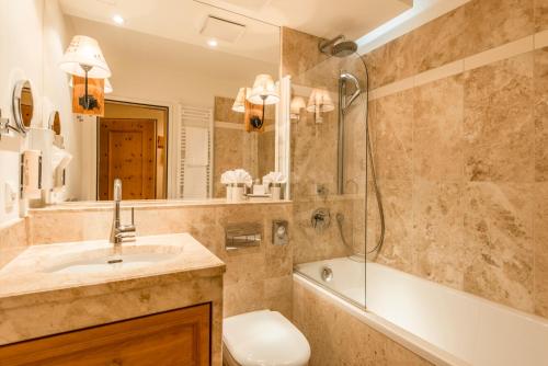 a bathroom with a sink, toilet and bathtub at La Val Hotel & Spa in Breil/Brigels