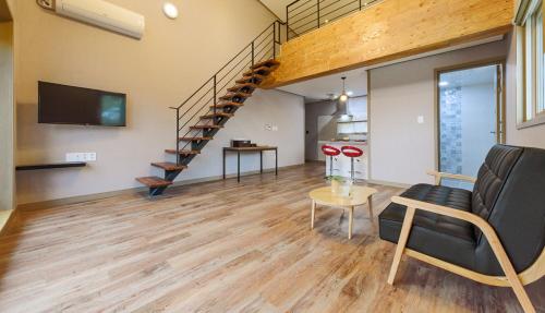 a living room with a staircase and a couch and a table at Gyeongpoen Pension in Gangneung