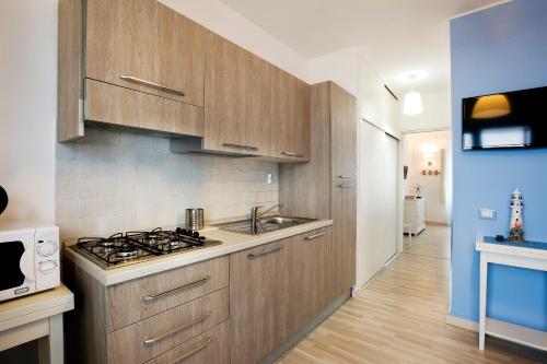 una cucina con armadi in legno, lavandino e piano cottura di Blue Marine Apartment a Pozzallo