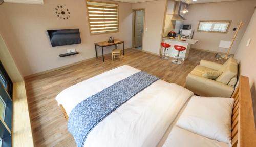 a bedroom with a large bed and a living room at Gyeongpoen Pension in Gangneung