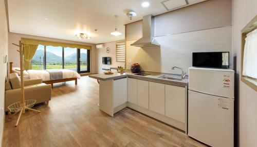 a kitchen with a sink and a refrigerator and a bedroom at Gyeongpoen Pension in Gangneung